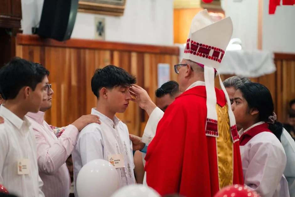 Bishop performing confirmation during a church ceremony with young participants.