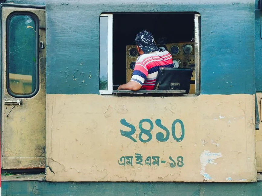 Train engineer inside a vintage locomotive cabin, showcasing railway history.