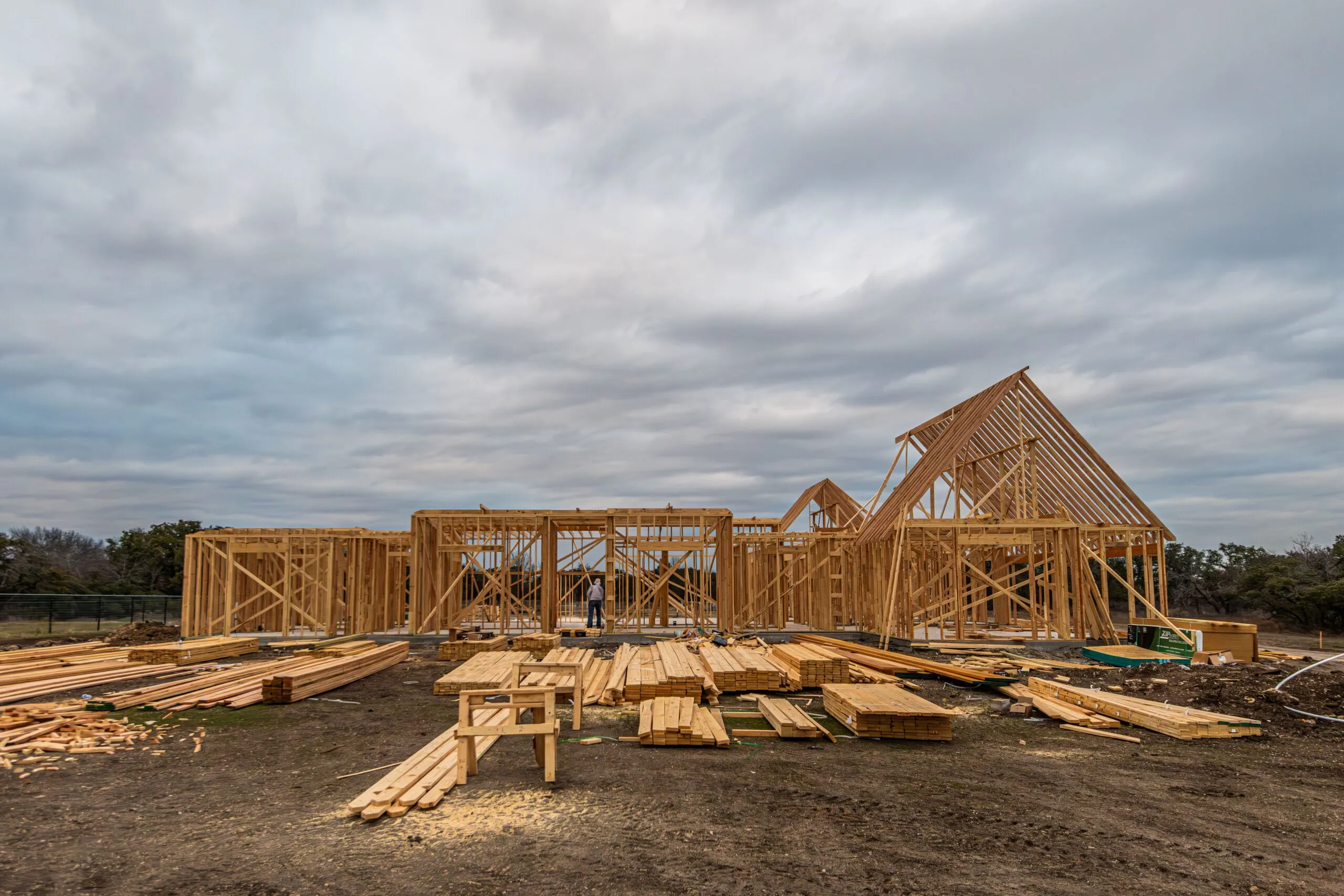 Wooden house framing under construction in Fort Worth, TX during a cloudy day.