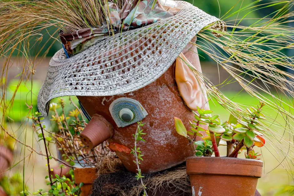 Colorful garden decoration featuring whimsical pot sculpture with plants.