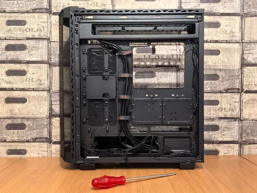 Open computer case ready for installation, with screwdriver placed nearby on desk.