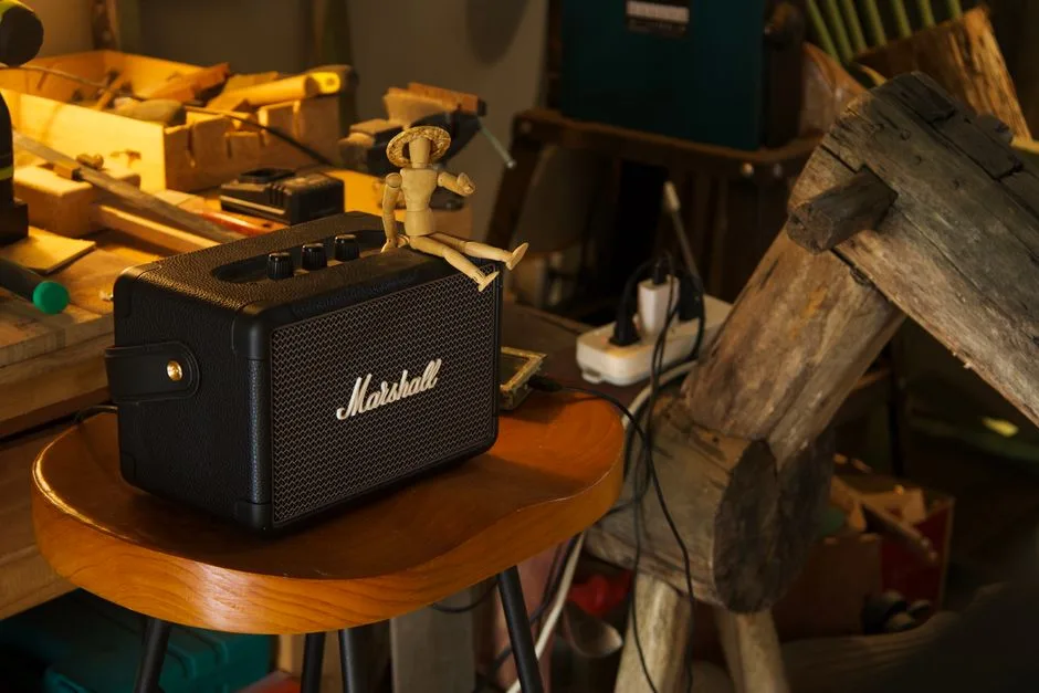 Cozy workshop scene with vintage amplifier and wooden mannequin in soft light.