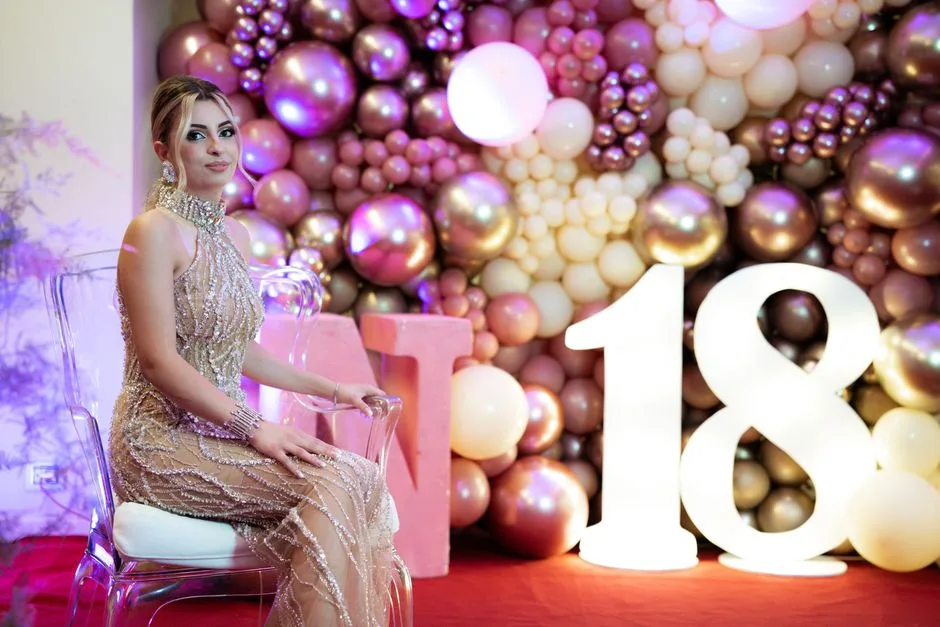 Stylish woman posing in elegant gown at vibrant 18th birthday party.