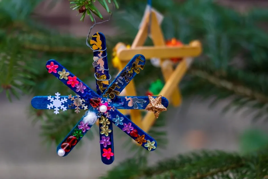 Vibrant handmade popsicle stick ornaments decorate a pine tree, celebrating the holiday season.