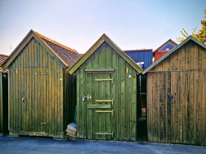Colorful wooden sheds in Assens, Denmark under clear summer sky.