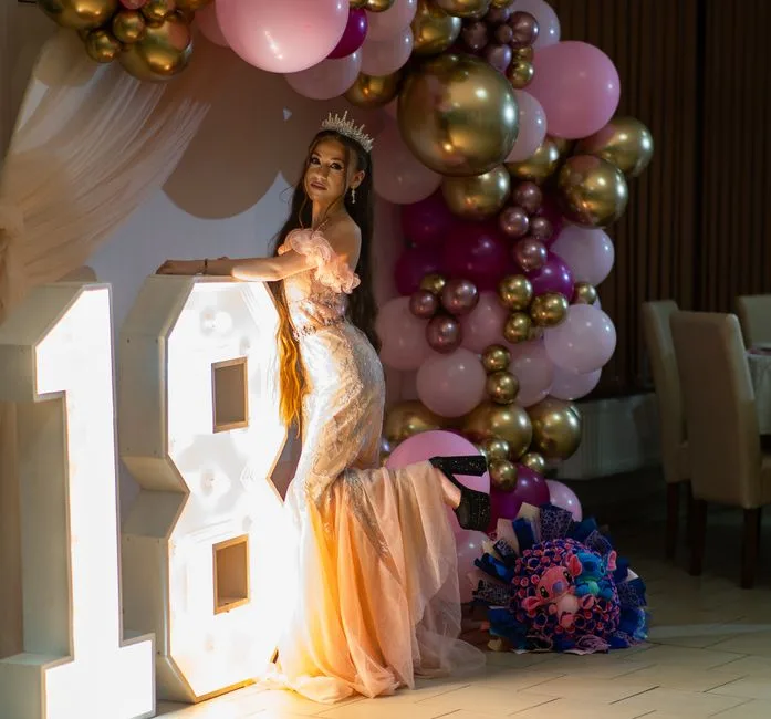 Glamorous young woman celebrating her 18th birthday with elegant decor and balloons.
