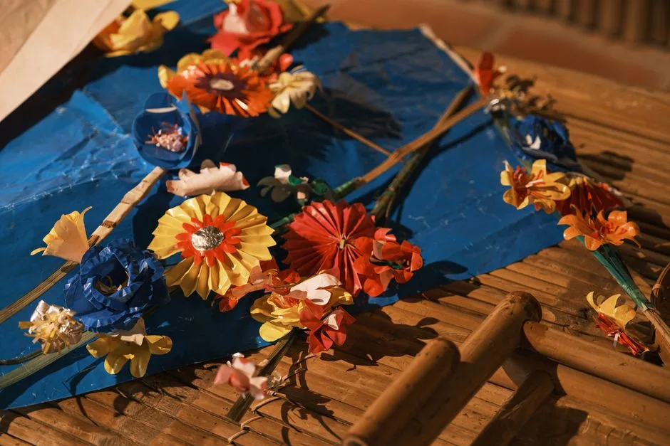 Vibrant handmade paper flowers arranged on a natural bamboo surface for a creative craft display.