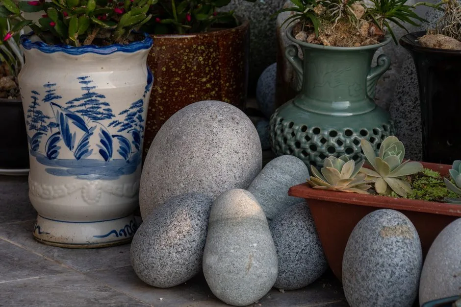 Artistic pottery with smooth stones and succulents in a garden setting, showcasing natural textures and colors.