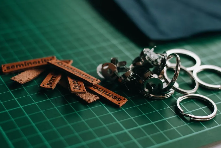 Detailed view of leather tags and metal rings on a green cutting mat, ideal for crafts and DIY projects.