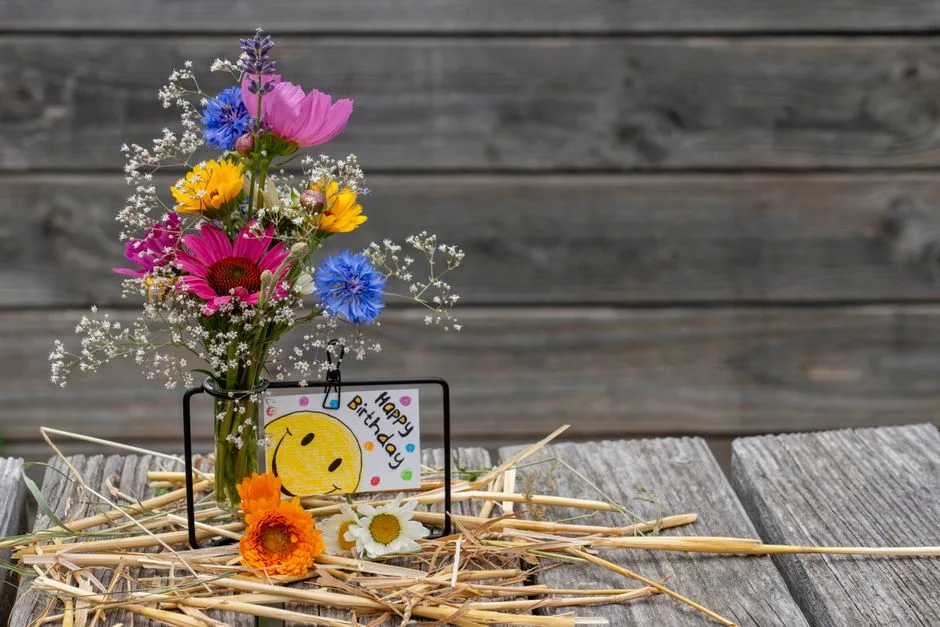 Vibrant floral bouquet with a birthday card on a rustic wooden table, perfect for celebrations.