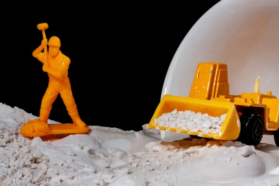 Close-up of toy worker and bulldozer in a conceptual construction scene with kinetic sand.