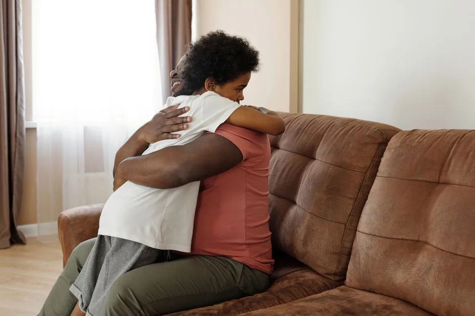 Father and son sharing a warm embrace on the sofa, expressing love and family togetherness.