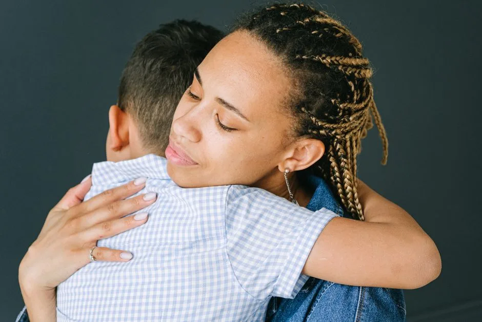 A loving mother holding and comforting her son in an emotional embrace indoors.