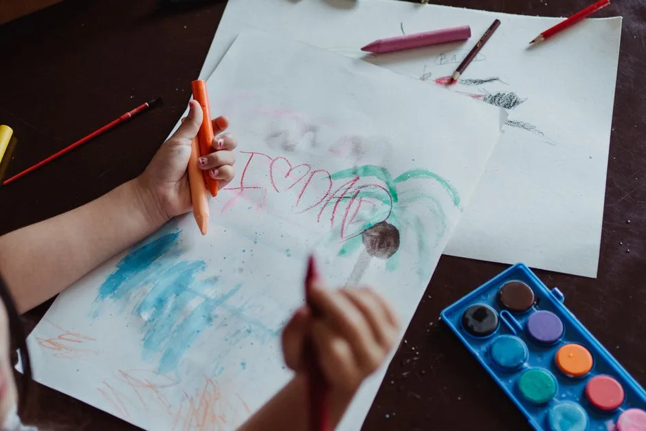 A child drawing with crayons and paints, expressing creativity and love for dad.