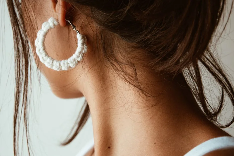 Close-up of a woman's ear adorned with a handmade crochet earring highlighting unique fashion style.