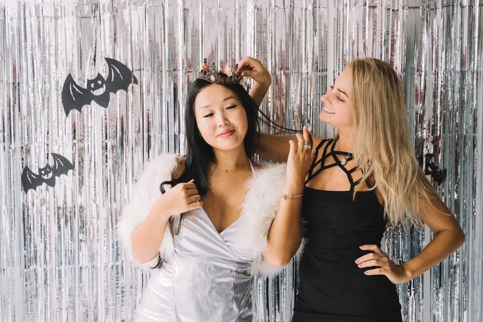 Two women in Halloween costumes enjoying a festive party with themed decorations.