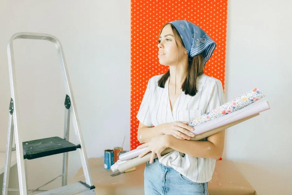 A young woman holding wallpaper is ready for room renovation indoors.
