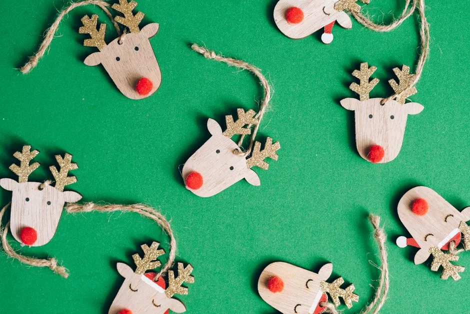 Wooden reindeer face ornaments on a green background, perfect for Christmas decor.