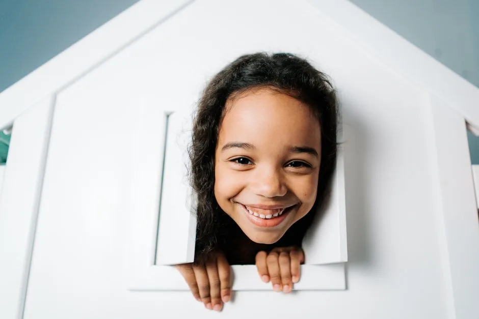 Joyful portrait of a young black girl smiling indoors in a playhouse. Vibrant and cheerful expression.