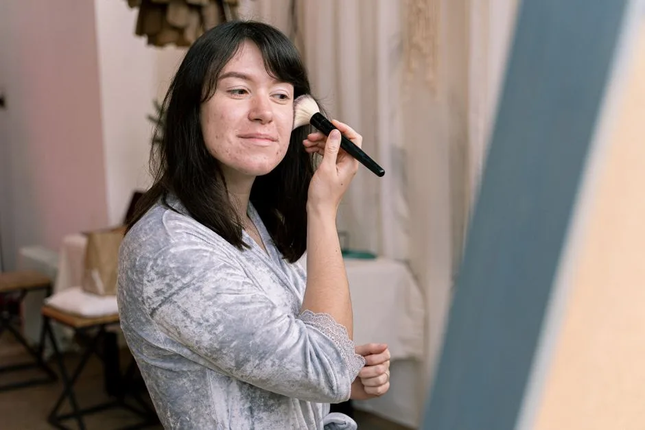 Teenage girl applying makeup indoors, enhancing her natural beauty.