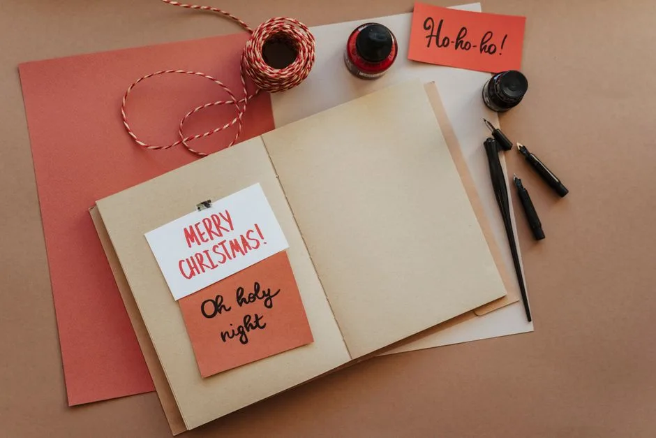 A warm and cozy still life of Christmas card crafting materials on a brown background.