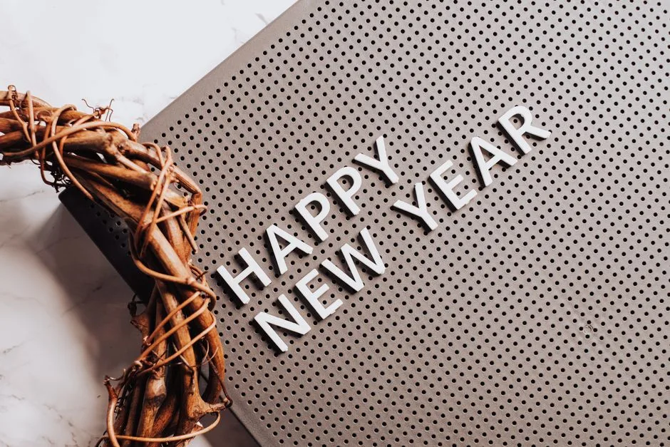 A stylish Happy New Year message with a decorative wreath on a marble surface.
