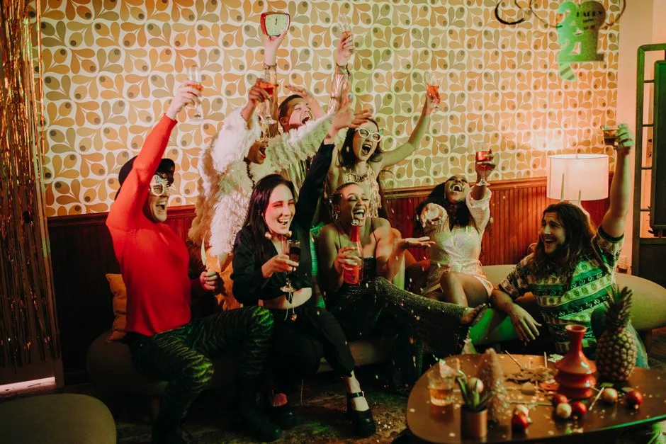 A lively group of friends celebrating with drinks and laughter in a cozy indoor setting.