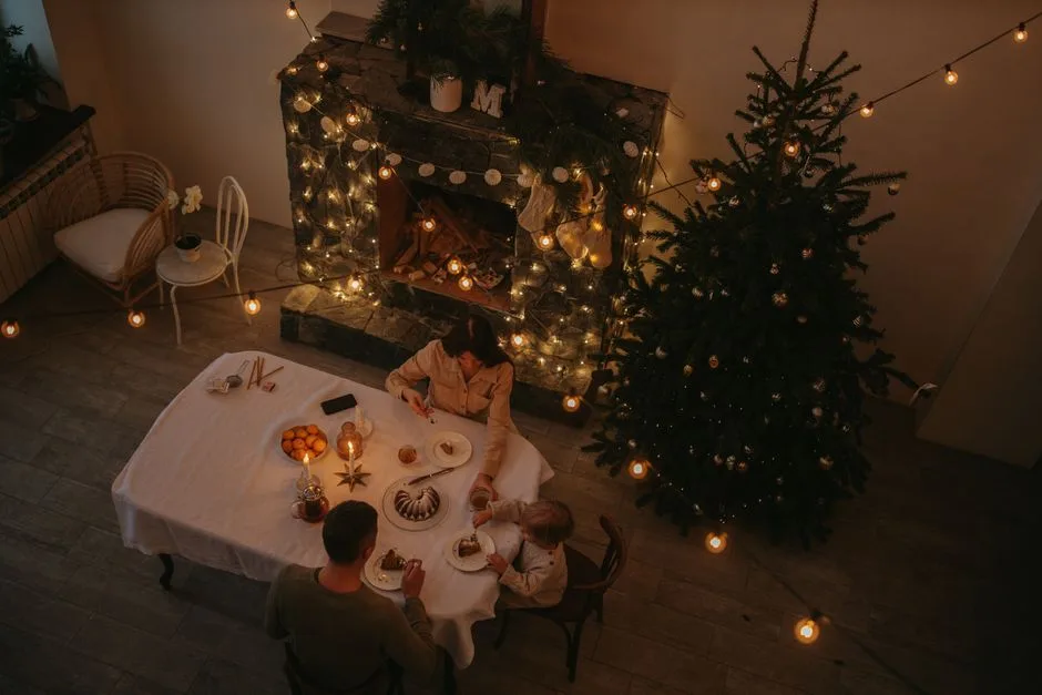 A warm family gathering around a festive dinner table, highlighted by Christmas lights and decorations.
