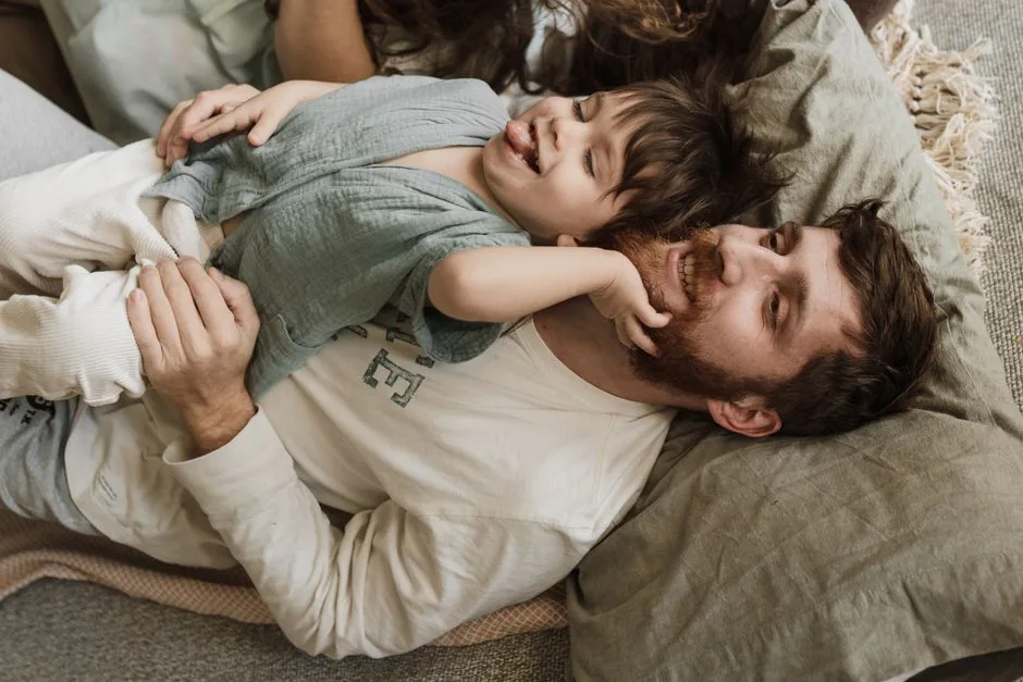 A joyful father and his son share a playful bonding moment indoors, filled with laughter.