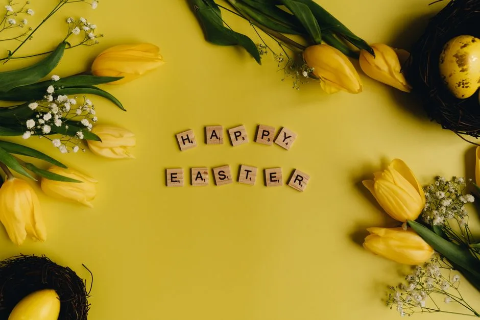 Bright yellow tulips and egg with Happy Easter message on a flat lay arrangement.