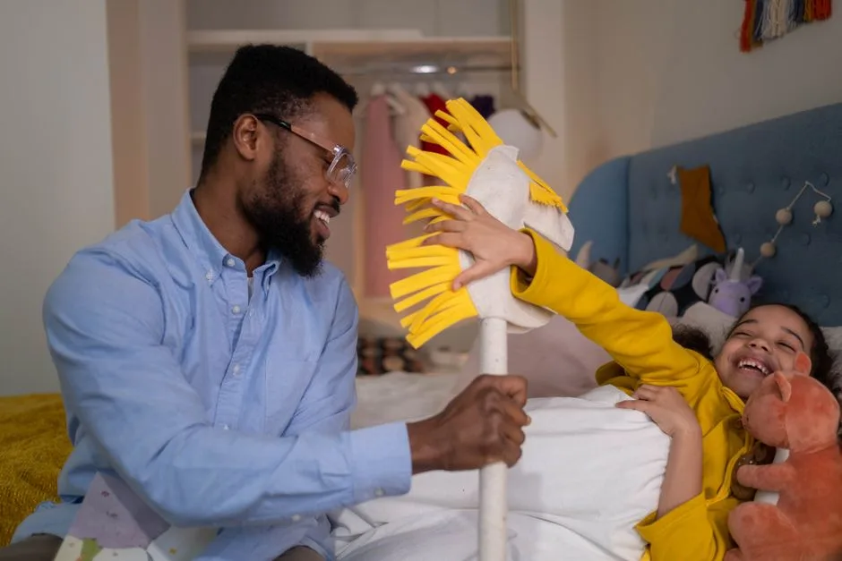 A cheerful father and daughter playing with a toy horse in a cozy bedroom setting.