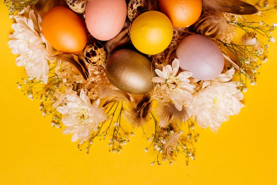 Brightly colored Easter eggs with white flowers on a vibrant yellow surface, creating a festive and cheerful scene.
