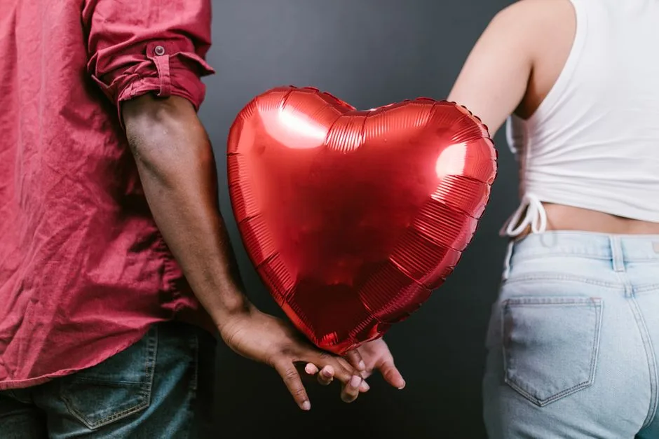 A couple holding a red heart-shaped balloon, symbolizing love and romance for Valentine's Day.