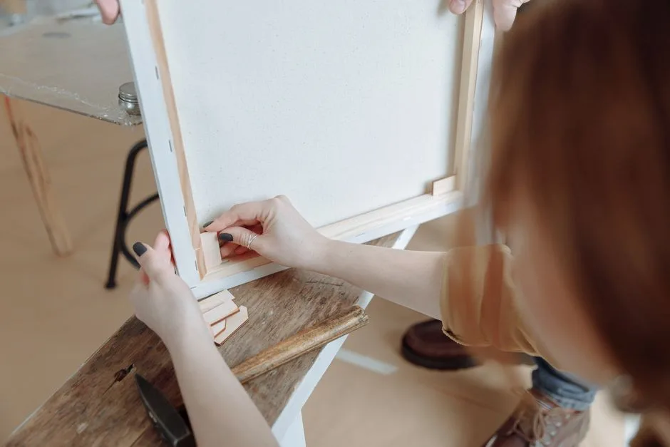 Close-up of hands assembling a canvas frame for a painting project indoors.