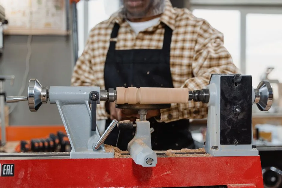 Close-up of a craftsman using a lathe in a workshop, showcasing woodworking skills.