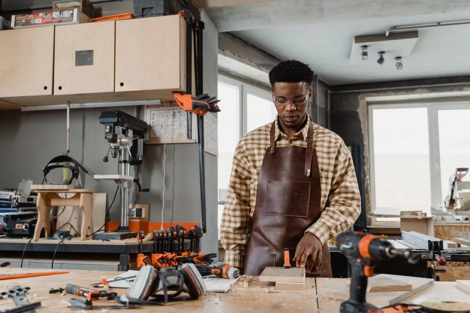 Craftsman in workshop using tools to create wooden pieces. Focused on precision and skill.