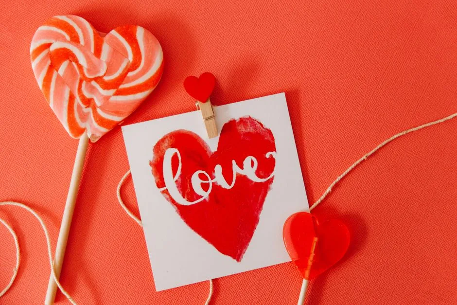 Heart-shaped lollipops and a 'love' card on a red background, perfect for Valentine's Day.