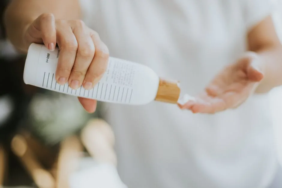 Close-up of a person pouring lotion from a bottle for skin care routine.