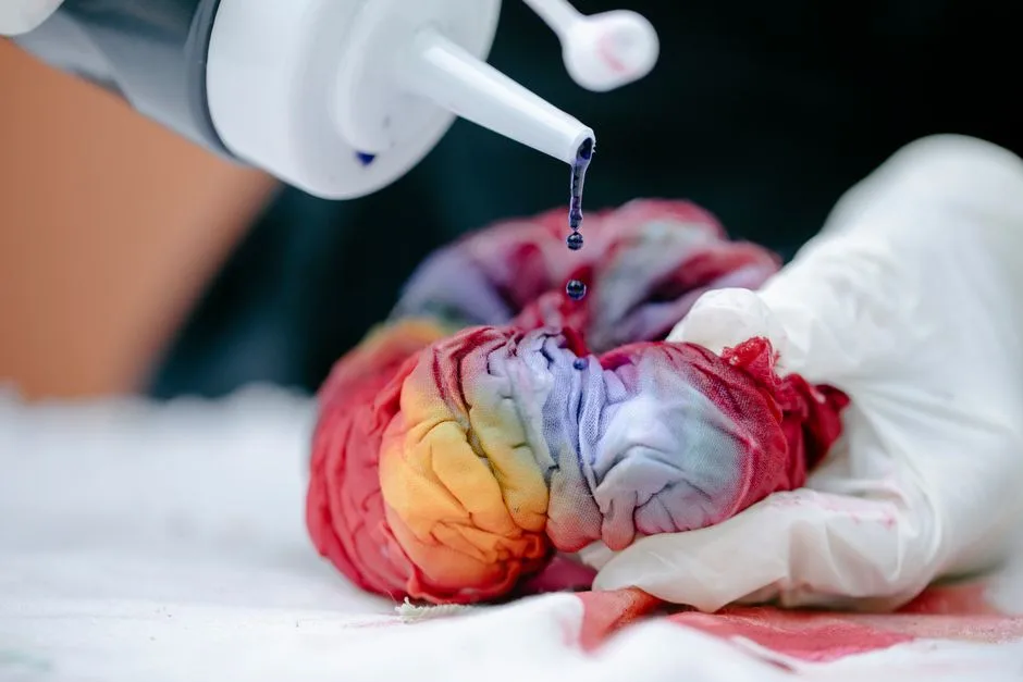 Close-up of a colorful tie-dye process using gloves and dye, showcasing a creative handmade fabric technique.