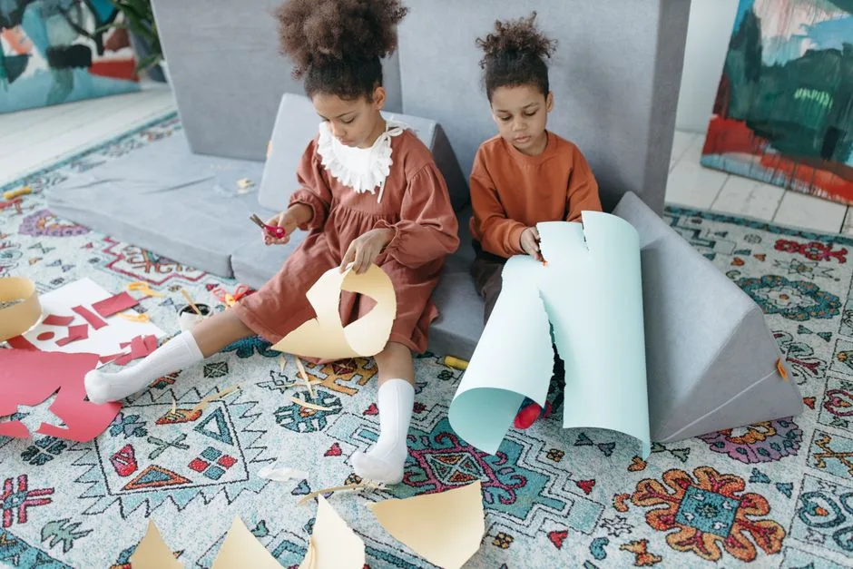 Two young sisters crafting with paper at home, showcasing creativity and bonding.