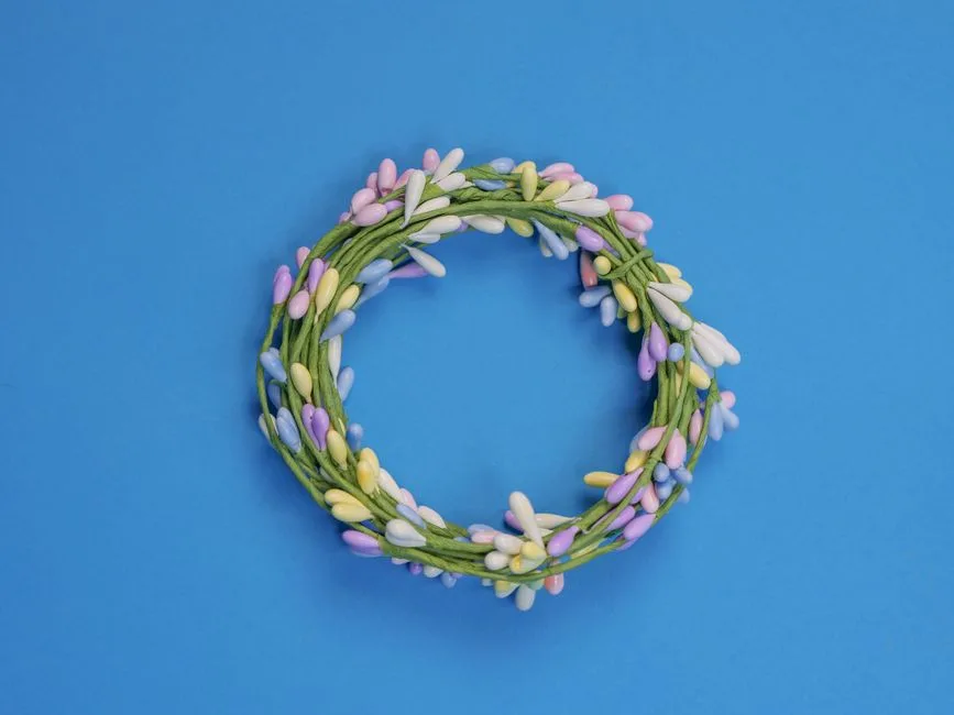 A vibrant wreath with pastel decorations on a blue backdrop, perfect for Easter celebrations.