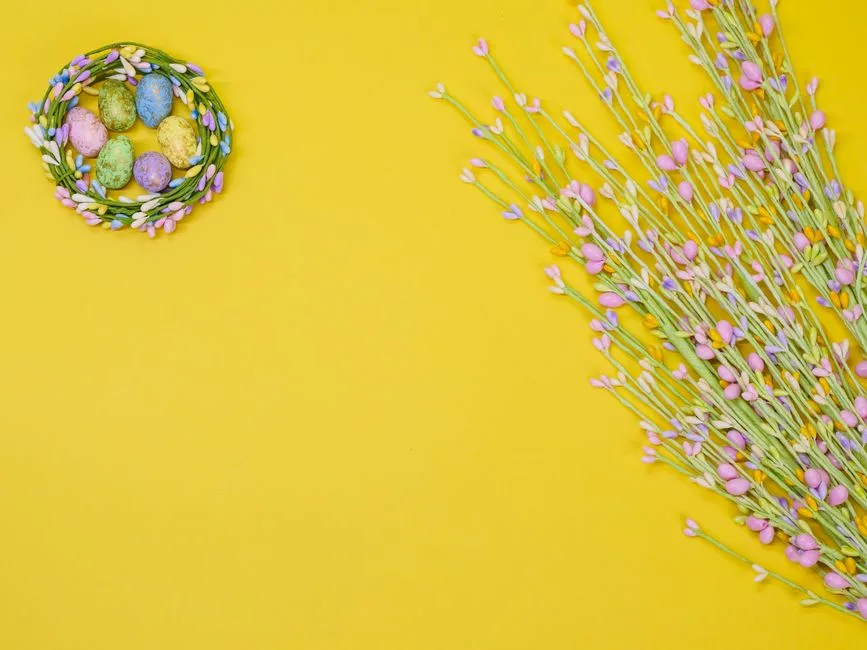 Decorative Easter eggs in a floral nest against a vibrant yellow background.
