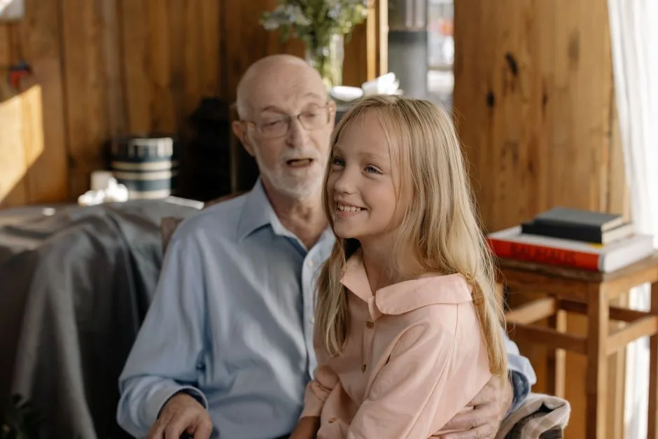 Heartwarming scene of a grandfather with his granddaughter indoors, sharing smiles and joy.