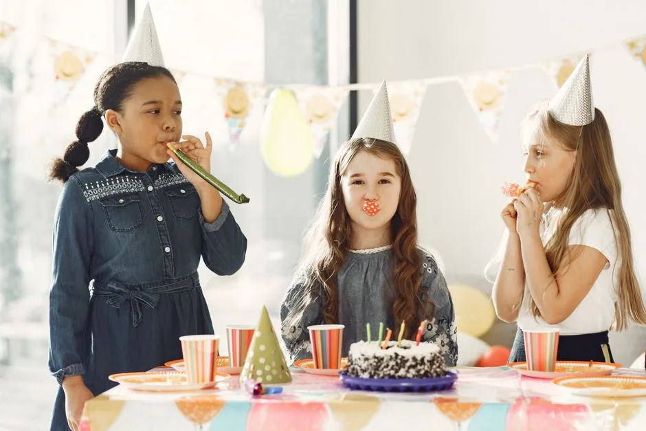 A lively birthday celebration with children in party hats enjoying cake and festivities indoors.
