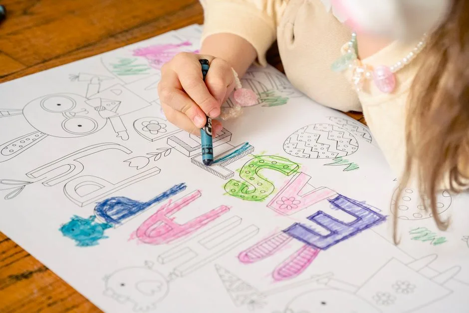 From above of crop anonymous little girl decorating greeting card with bright crayons at home