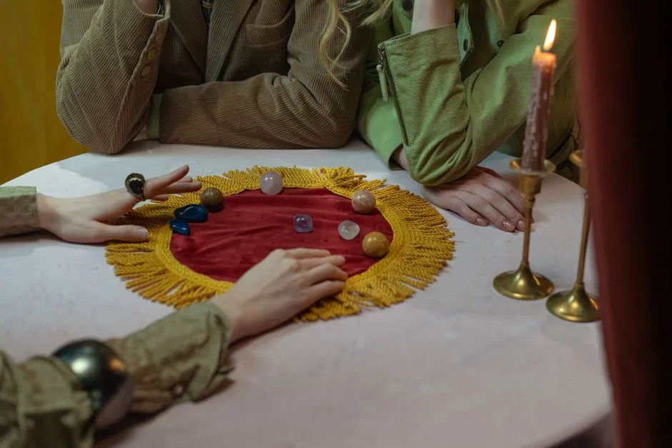 A close-up scene of a mystical fortune telling session with candles, crystals, and people's hands on a table.
