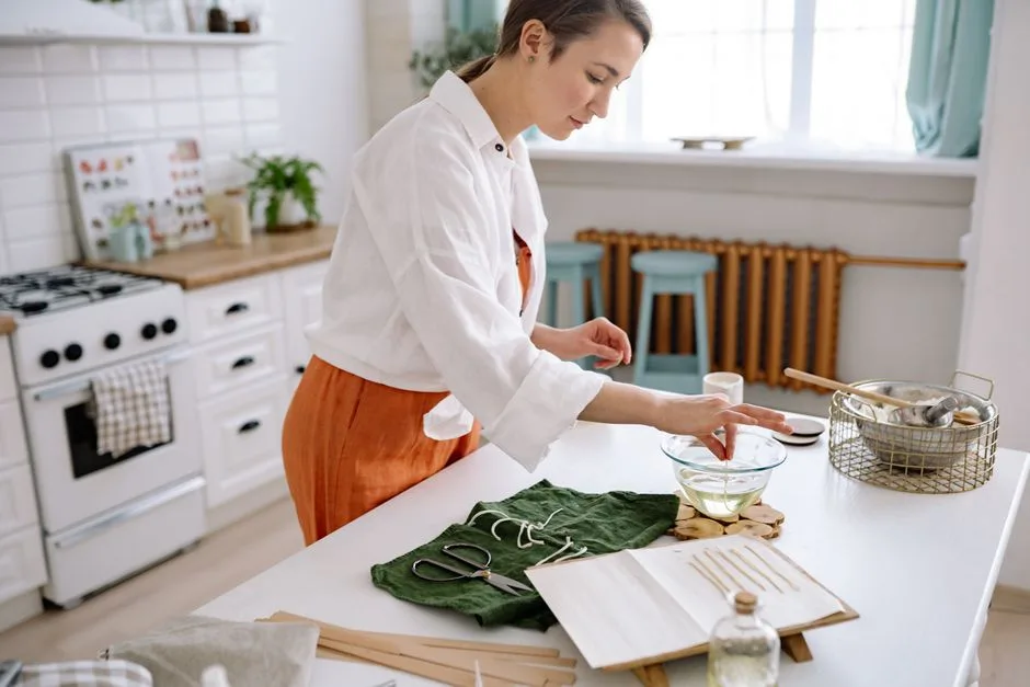 A woman handcrafting soy candles in a modern kitchen, showcasing artistry and craftsmanship.