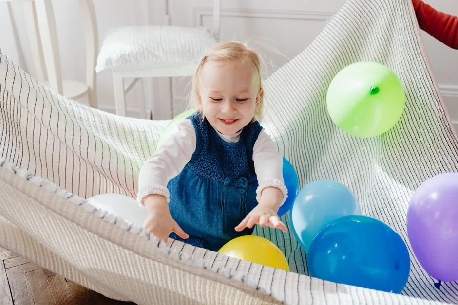 A cheerful young girl enjoying a playful moment with colorful balloons indoors.