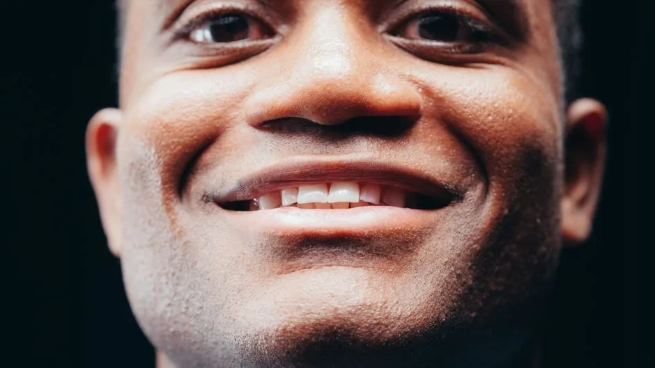 Detailed close-up photo of a smiling man's face capturing joy and positivity.