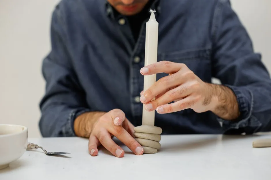 Close-up of hands shaping a clay candle holder in a creative studio.